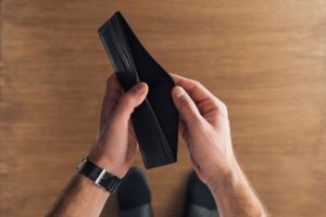 top view of man holding empty wallet on wooden background