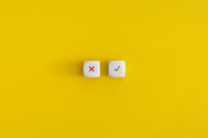 Cross and check mark on a white cubes on yellow background.
